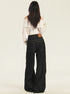 A woman shown from behind wearing cream off-shoulder folded neckline blouse and high-waisted black wide-leg jeans with leather patch detail