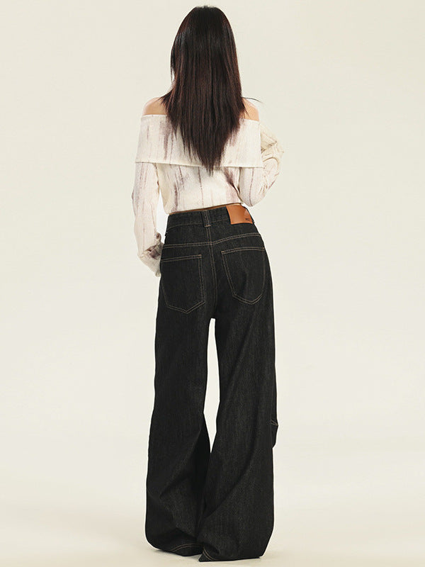 A woman shown from behind wearing cream off-shoulder folded neckline blouse and high-waisted black wide-leg jeans with leather patch detail