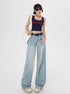 Model with white bag wearing navy branded tank top, wide-leg light wash jeans, and platform sneakers