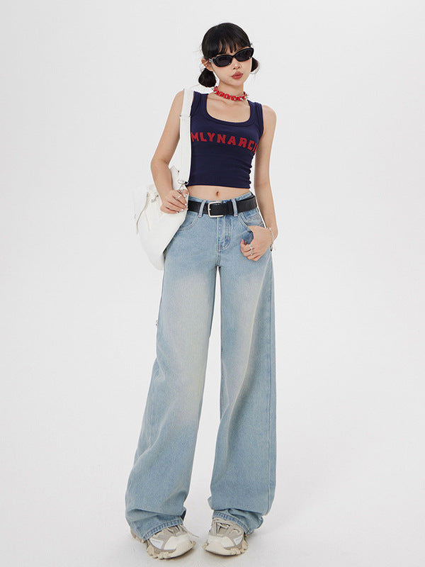 Model with white bag wearing navy branded tank top, wide-leg light wash jeans, and platform sneakers