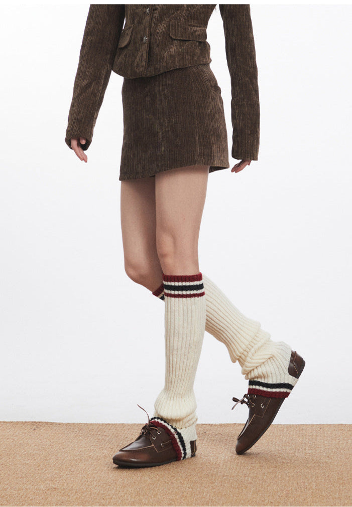 Side profile of model wearing brown corduroy mini skirt, white socks, and vintage-style loafers.