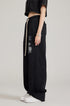 Side profile of model in black two-piece set with oversized sweatpants featuring graphic detail and chain bracelet