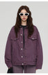 A woman wearing white oval sunglasses and purple oversized denim jacket against white background with relaxed styling