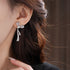 Detailed side view of silver bow earring with crystal details worn on ear, showing elegant shape against dark hair