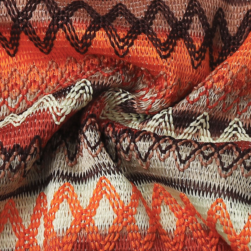 A detailed view of an orange and brown knit fabric with a geometric pattern and intricate woven texture.
