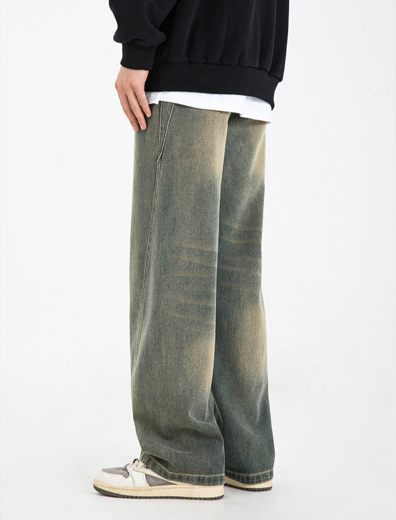 A model wearing olive-green wide-leg jeans with unique seam detail, black sweatshirt layered over white tee, paired with retro gray and white sneakers
