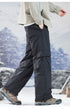 Profile view of wide-leg black cargo pants styled with light jacket, demonstrating movement and fit in outdoor setting