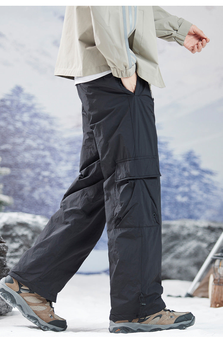 Profile view of wide-leg black cargo pants styled with light jacket, demonstrating movement and fit in outdoor setting