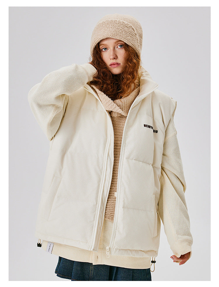 Woman with red curly hair wearing cream puffer jacket with knit beanie and scarf, showcasing minimal winter style against white background