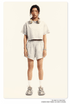 Model in off-white cropped tee and matching shorts with elastic waist, white socks and gray sneakers