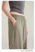 Side view of person's hand in pocket of taupe cargo pants with elasticated waistband shown with gray crop top