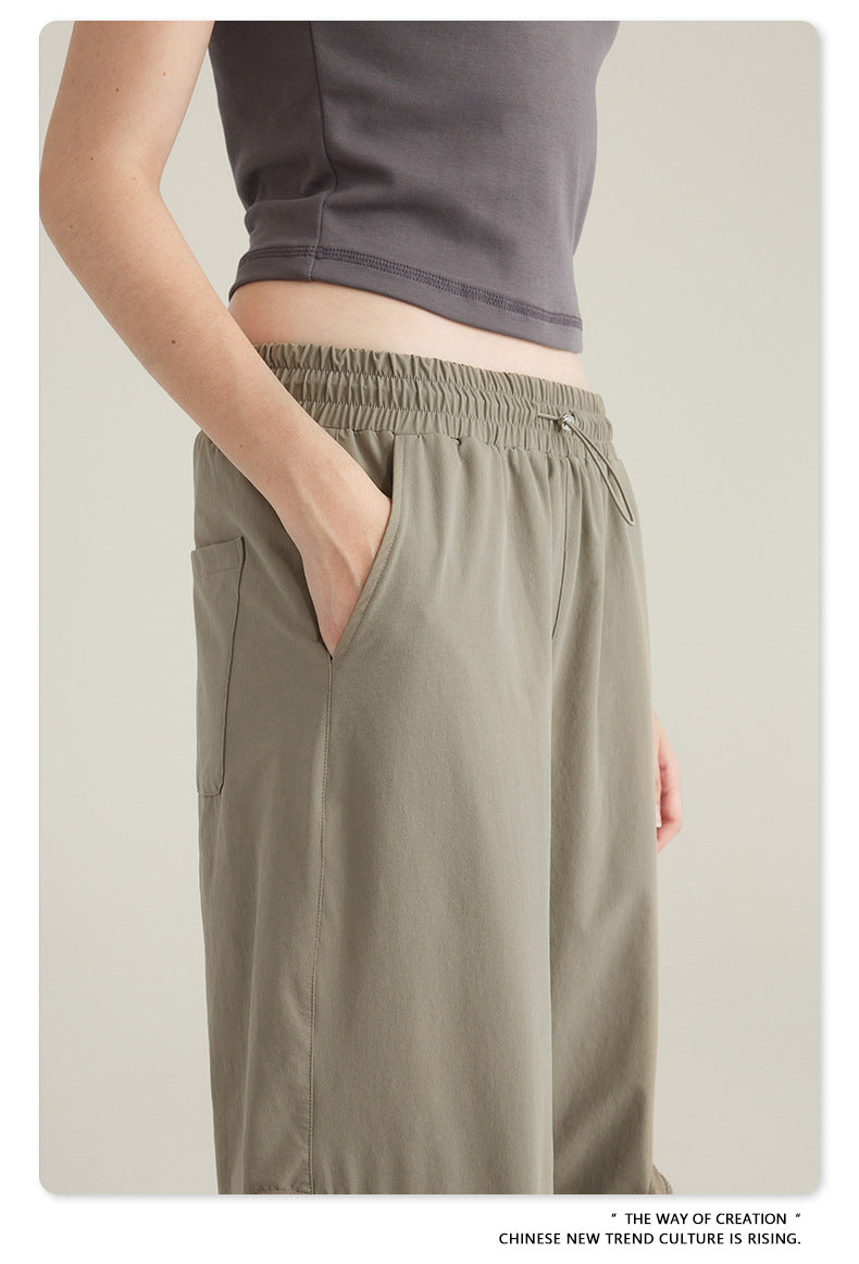 Side view of person's hand in pocket of taupe cargo pants with elasticated waistband shown with gray crop top