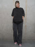 Person wearing a dark gray outfit against a plain wall