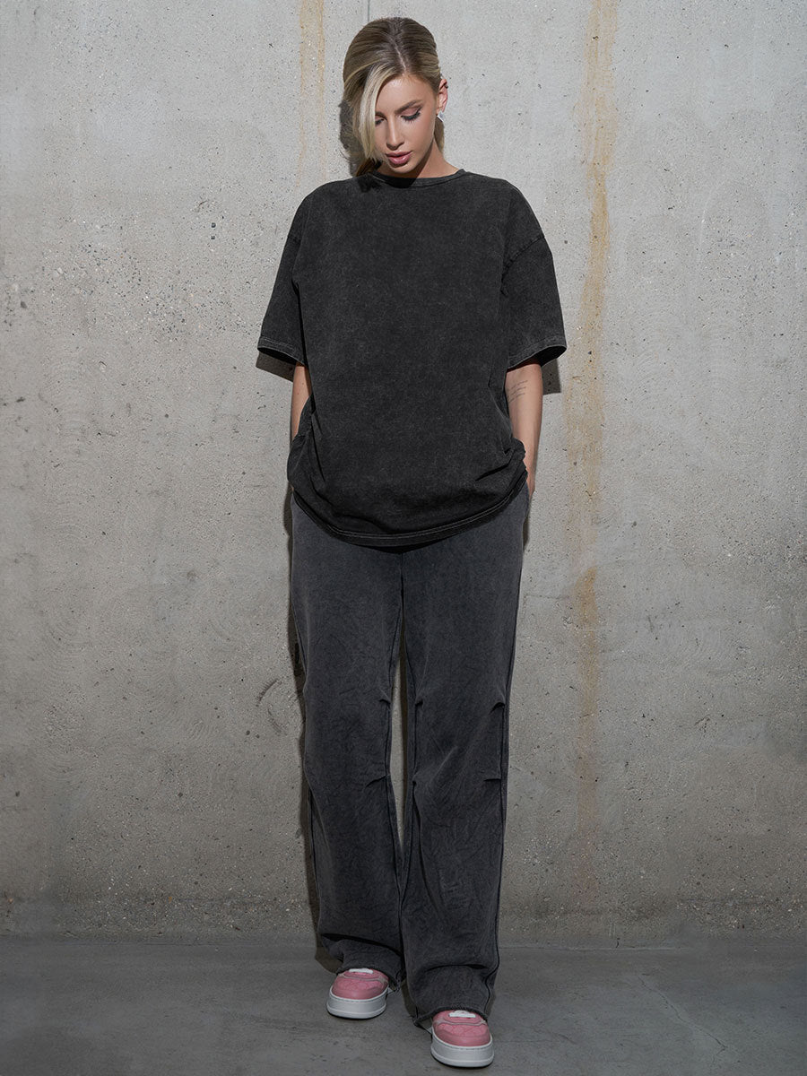 Person wearing a dark gray outfit against a plain wall