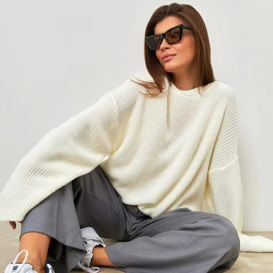 Woman in white oversized knit sweater and grey wide-leg pants with casual sunglasses