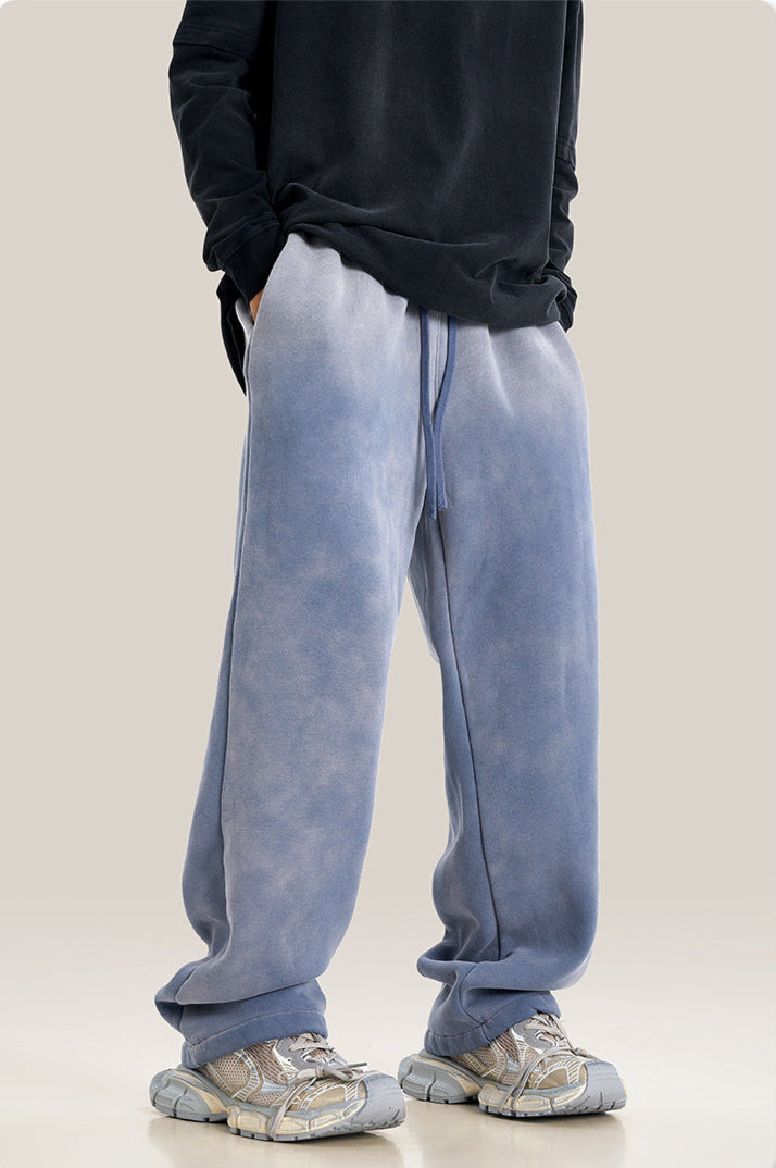 Model wearing light blue wide-leg sweatpants with black hoodie and gray athletic shoes against neutral background