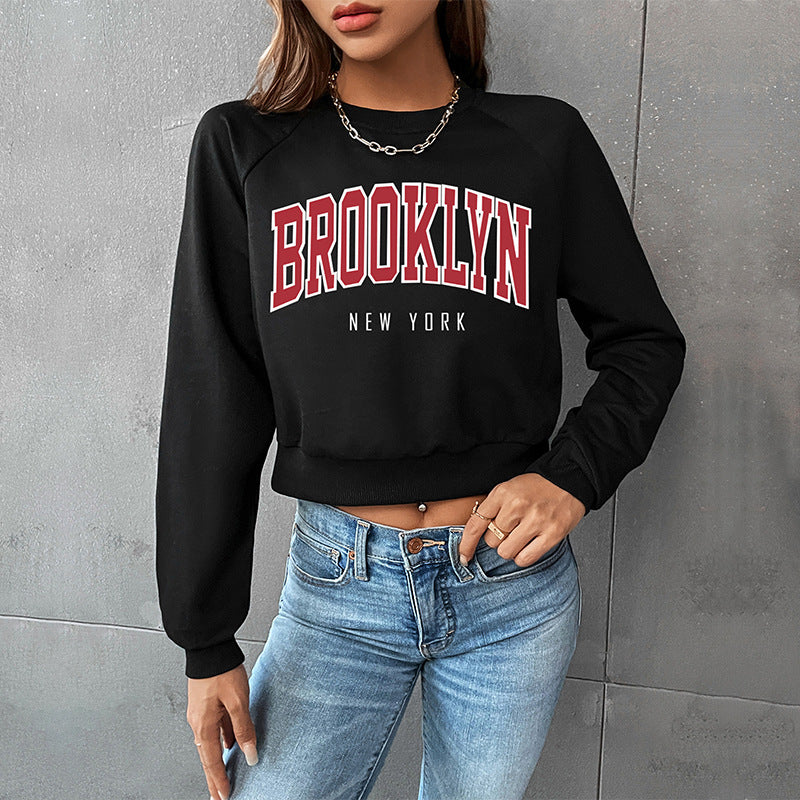 Black crop sweatshirt featuring BROOKLYN text in varsity style, styled with high-waisted denim and silver chain