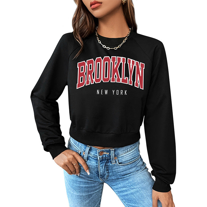 Front detail of varsity-style Brooklyn sweatshirt with red and white lettering, styled casually with denim