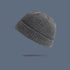 A heather gray ribbed knit beanie with folded cuff floating against slate gray background, showing versatile winter hat style