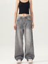 A woman wearing a black crop tank top and gray wide-leg jeans stands against a white background