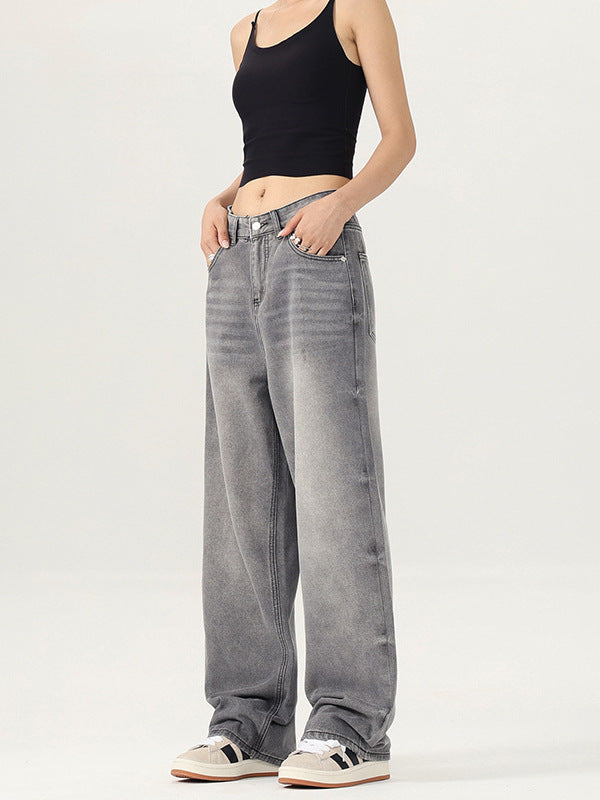 A woman modeling gray wide-leg jeans with a black crop top, standing against a plain white background