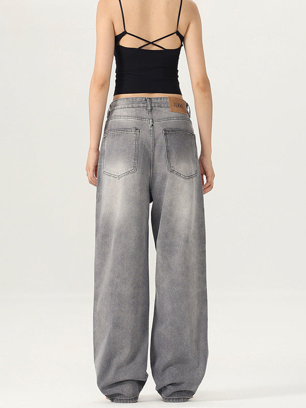 A woman shown from behind wearing cross-strap black tank top and gray wide-leg jeans with a leather waist patch
