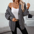 Gray cable knit cardigan styled with white cami top and black pants, featuring gold buttons and layered necklaces for casual chic look