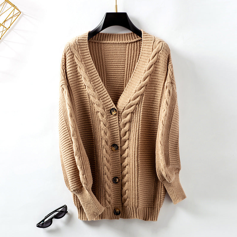 Beige chunky knit cardigan with cable pattern and button front displayed on hanger, styled with black sunglasses