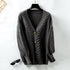 Charcoal gray oversized cardigan with cable knit design and wooden buttons, flat lay product photography