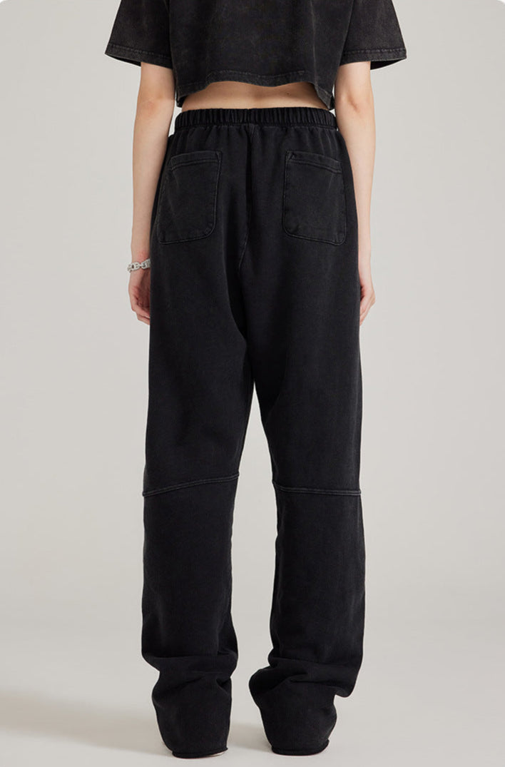 Back view of black sweatpants showing patch pockets and relaxed fit. Paired with cropped black top