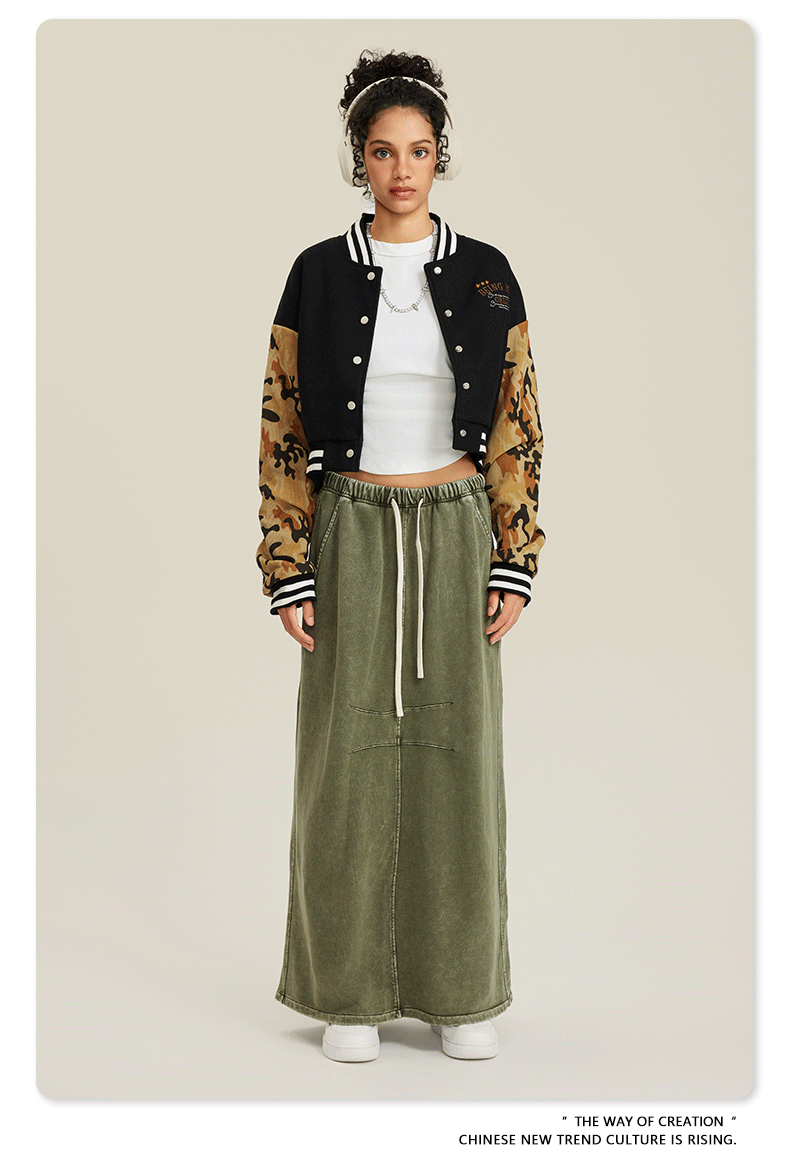 Black cropped varsity jacket with tan camouflage sleeves, white stripe trim, and embroidered collegiate-style logo
