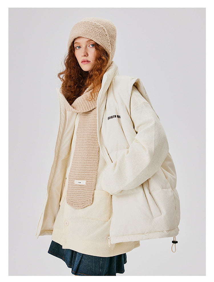 Woman in cream puffer jacket with matching knit hat and scarf, partially unzipped to show layering against white background