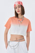 Side angle of model in coral ombré crop top with white shorts and chain belt