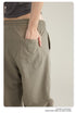Detail shot of hand in pocket of taupe cargo pants with olive oversized shirt, showing drawstring waist