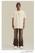 Image 1: Model wearing oversized cream t-shirt, wide-leg brown pants with drawstring, white sneakers against neutral backdrop