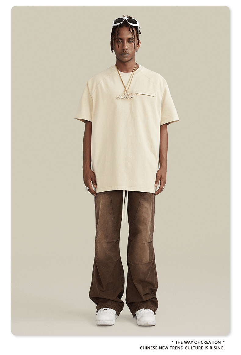 Image 1: Model wearing oversized cream t-shirt, wide-leg brown pants with drawstring, white sneakers against neutral backdrop