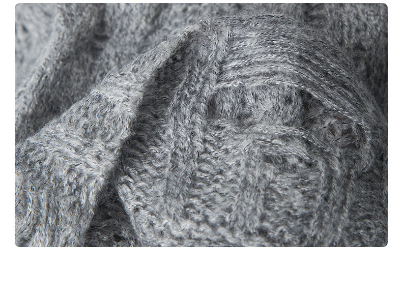 Extreme close-up of grey sweater's cable knit pattern showing detailed texture and stitch construction