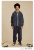 Man in navy zip-up hoodie and sweatpants with silver chain and Nike sneakers on beige background.gif