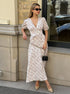 Woman leaning on wall in white floral v-neck puff sleeve maxi dress