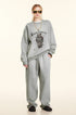 Front view of blonde model in light gray Winding Decoration sweatshirt, matching pants, gold sunglasses, gold chain necklace, dark slippers
