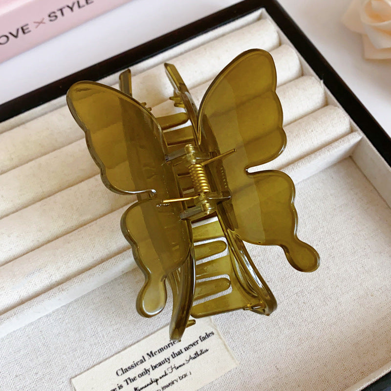 A translucent green butterfly-shaped hair claw with delicate details, displayed on a fabric-lined tray.