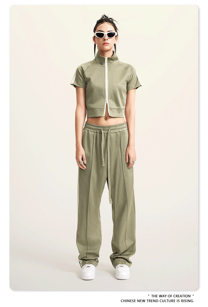 Woman in sage green crop jacket and pants, wearing white sunglasses