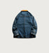 Back view of blue denim jacket with brown collar showing detailed seam work on light background