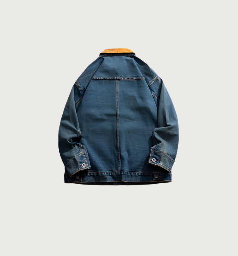 Back view of blue denim jacket with brown collar showing detailed seam work on light background