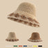 A beige woven bucket hat with a decorative brown floral pattern along the brim, displayed against a neutral background with smaller variations below.