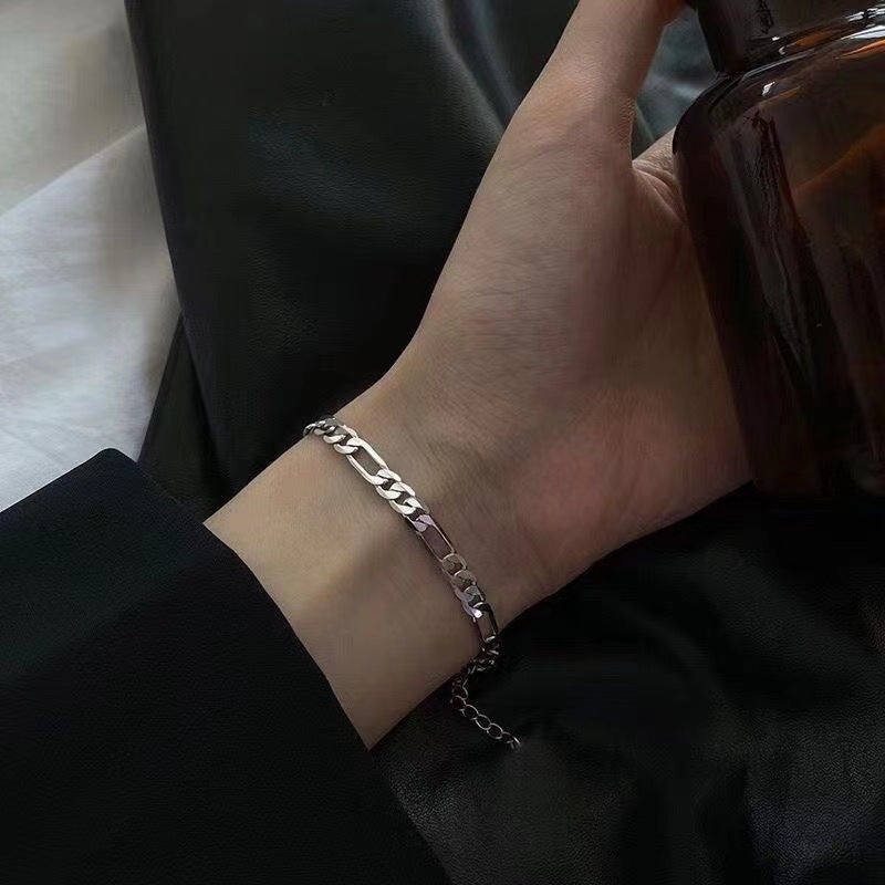 Silver Figaro chain bracelet on wrist, close-up view