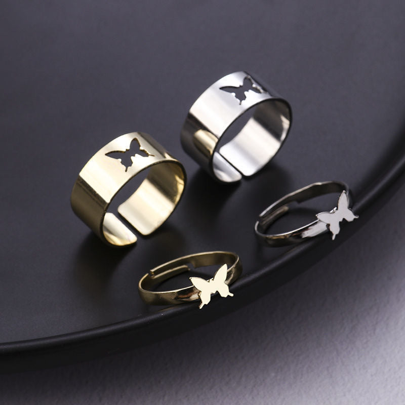 Collection of butterfly rings in gold and silver finishes shown on black surface: two wide bands and two delicate bands
