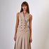 A woman wearing a beige double-breasted sleeveless vest and matching pleated midi skirt, posing against a white background