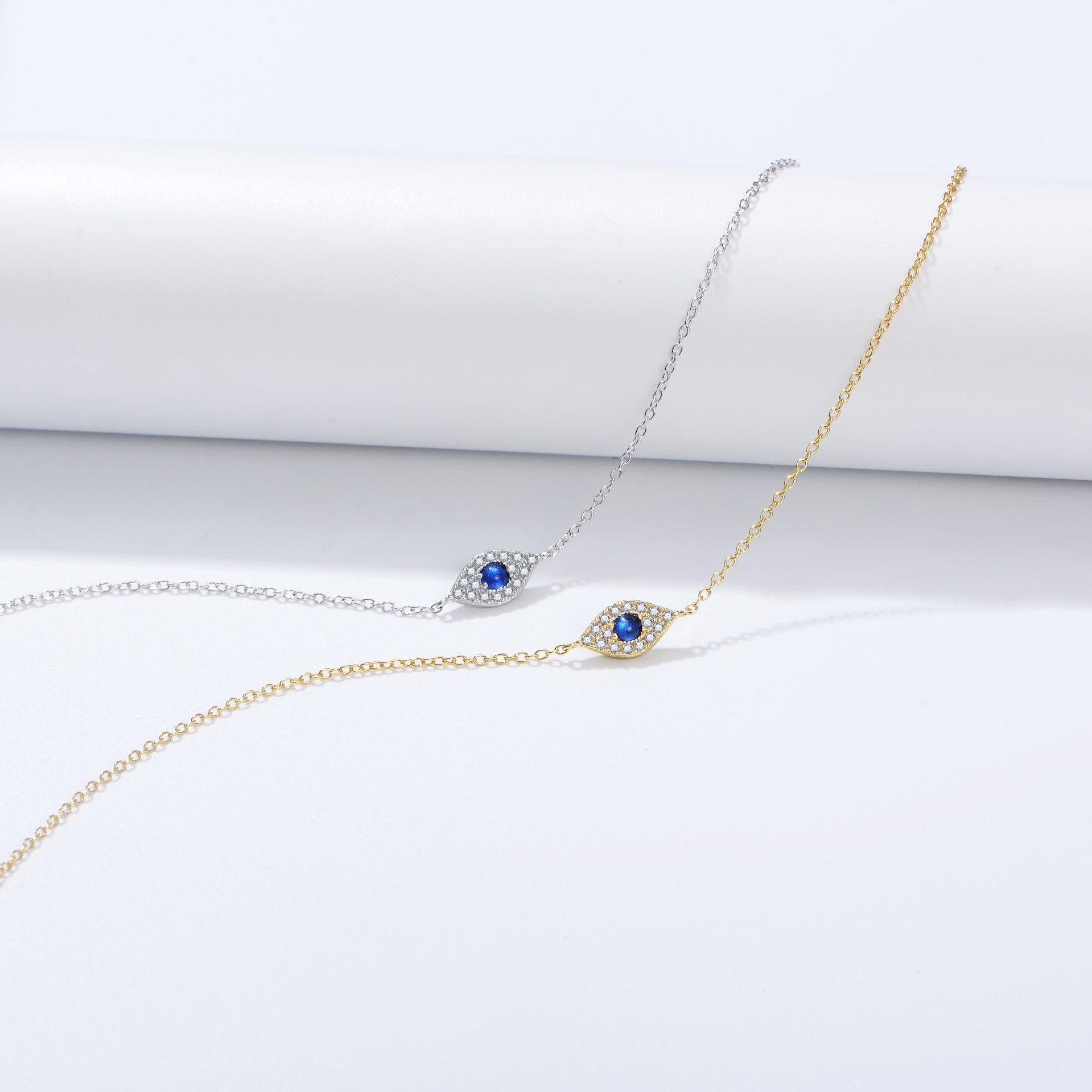 Evil eye bracelets in silver and gold options, both featuring blue sapphire centers with diamond accents on delicate chains