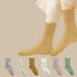 A model wearing cream crew socks with white pants, shown above a collection of six different colored socks in gray, ivory, camel, white, lilac, and sage green